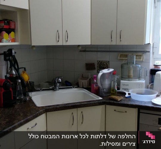 מטבח עם ארונות לבנים, כיור ומכשירי חשמל